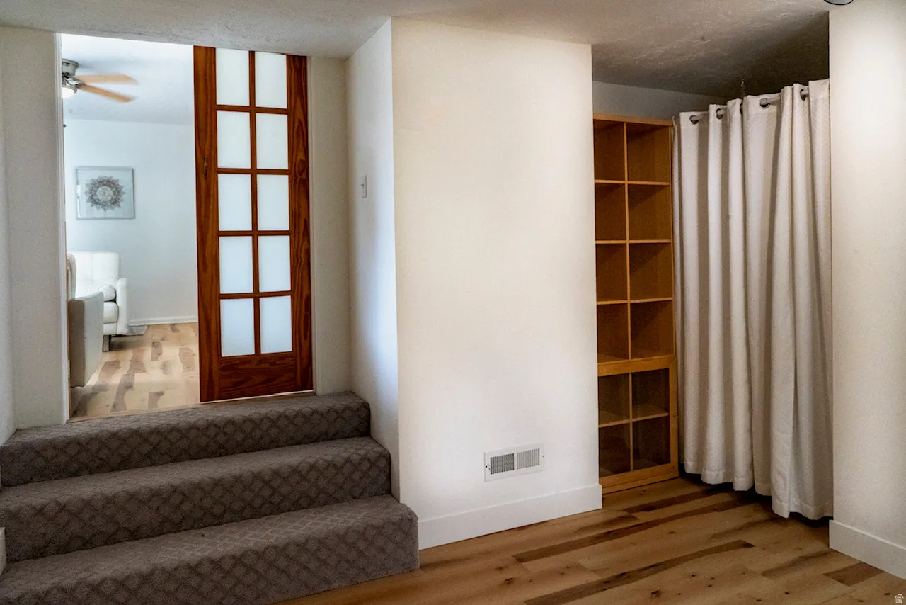 Sunken room featuring three carpeted steps, a wood-finish pocket door with frosted glass panels, and wood-finish flooring