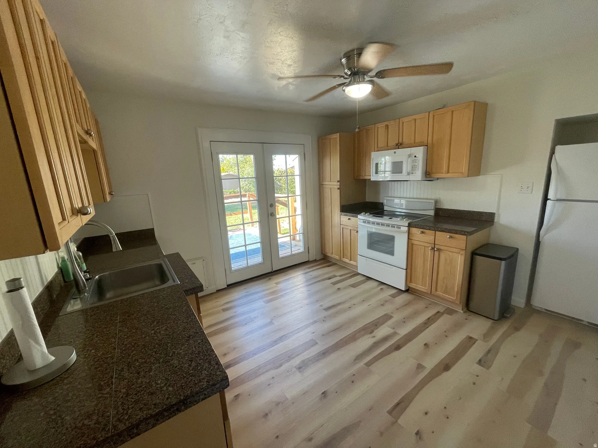 Kitchen featuring light wood cabinetry, dark speckled countertops, and wood-finish flooring
