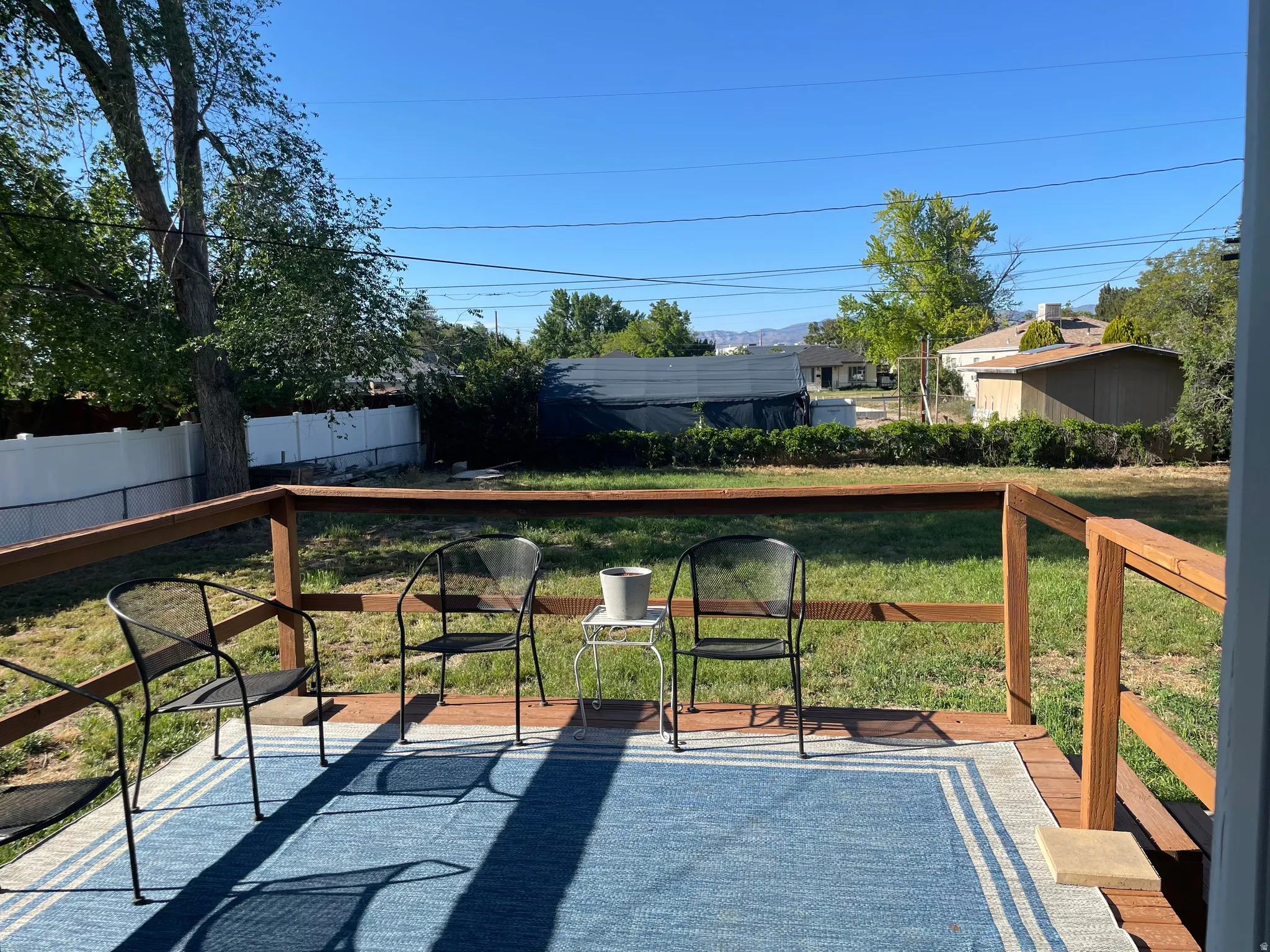 Wood deck with a natural finish, featuring a wooden railing and a spacious grassy area beyond