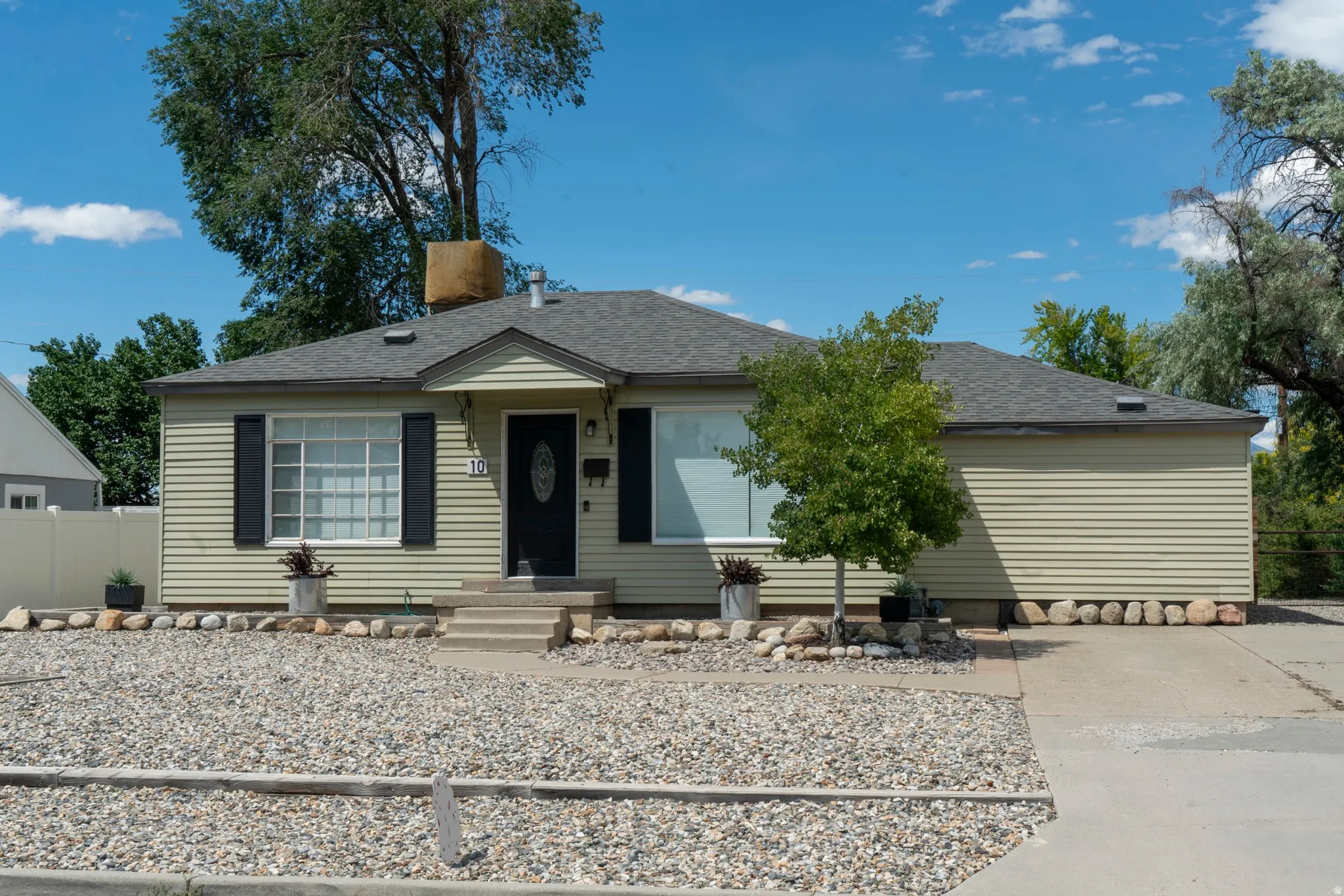 Ranch-style exterior with light-colored horizontal siding, a dark asphalt shingle roof, and a prominent front entry with a black door