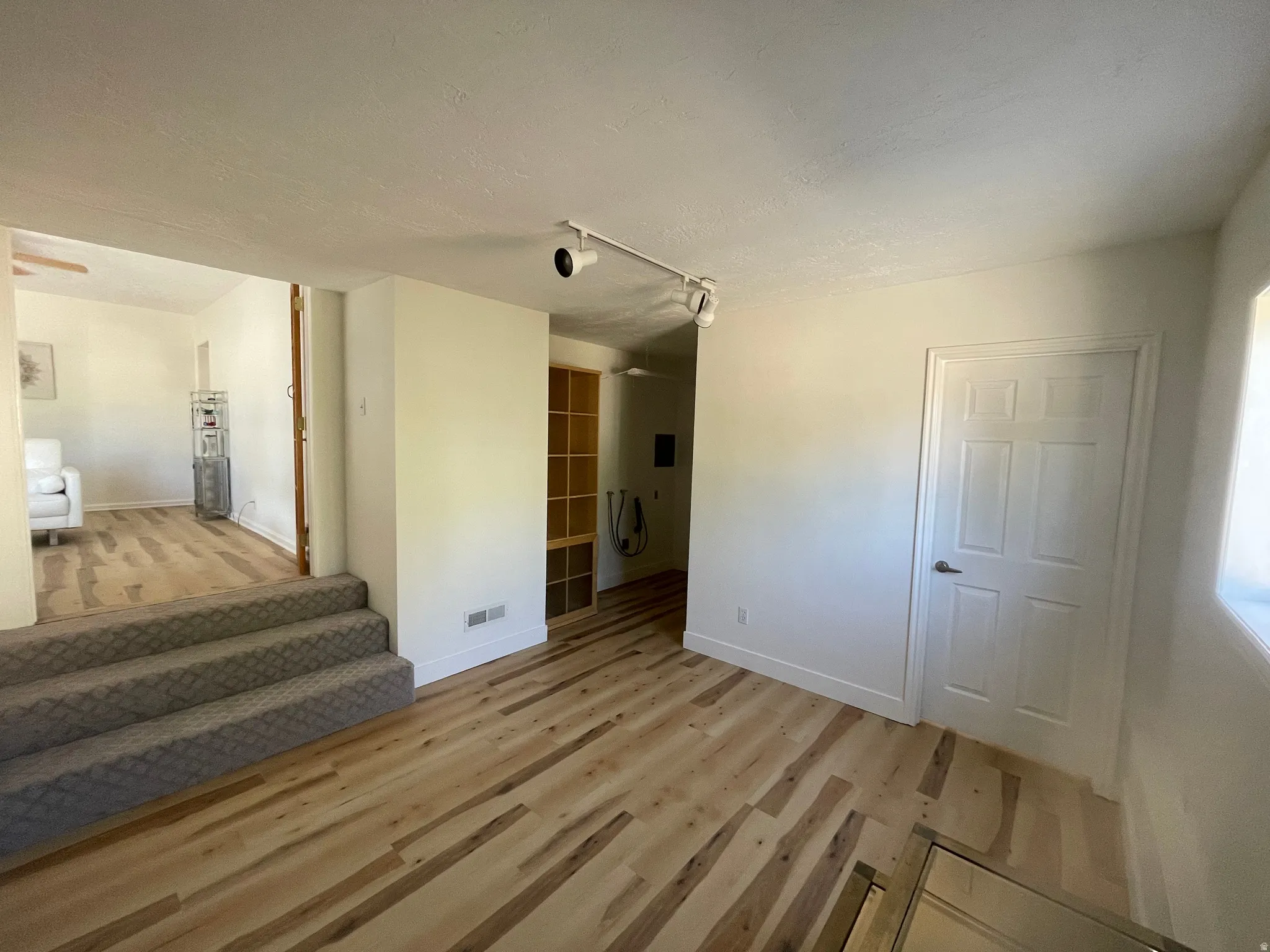 Wood-finish flooring throughout, featuring a multi-level design with carpeted steps