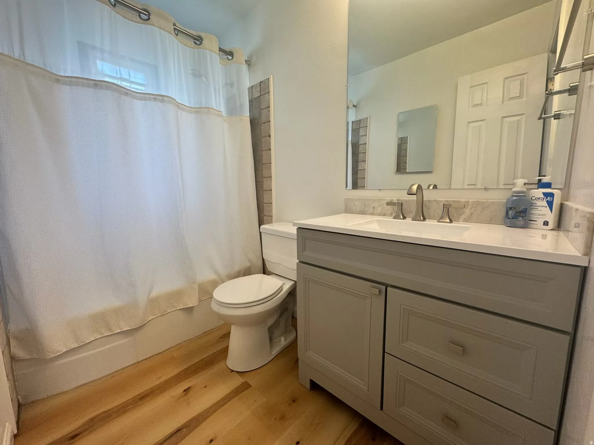 Bathroom featuring a grey vanity with a white countertop, undermount sink, and brushed nickel faucet