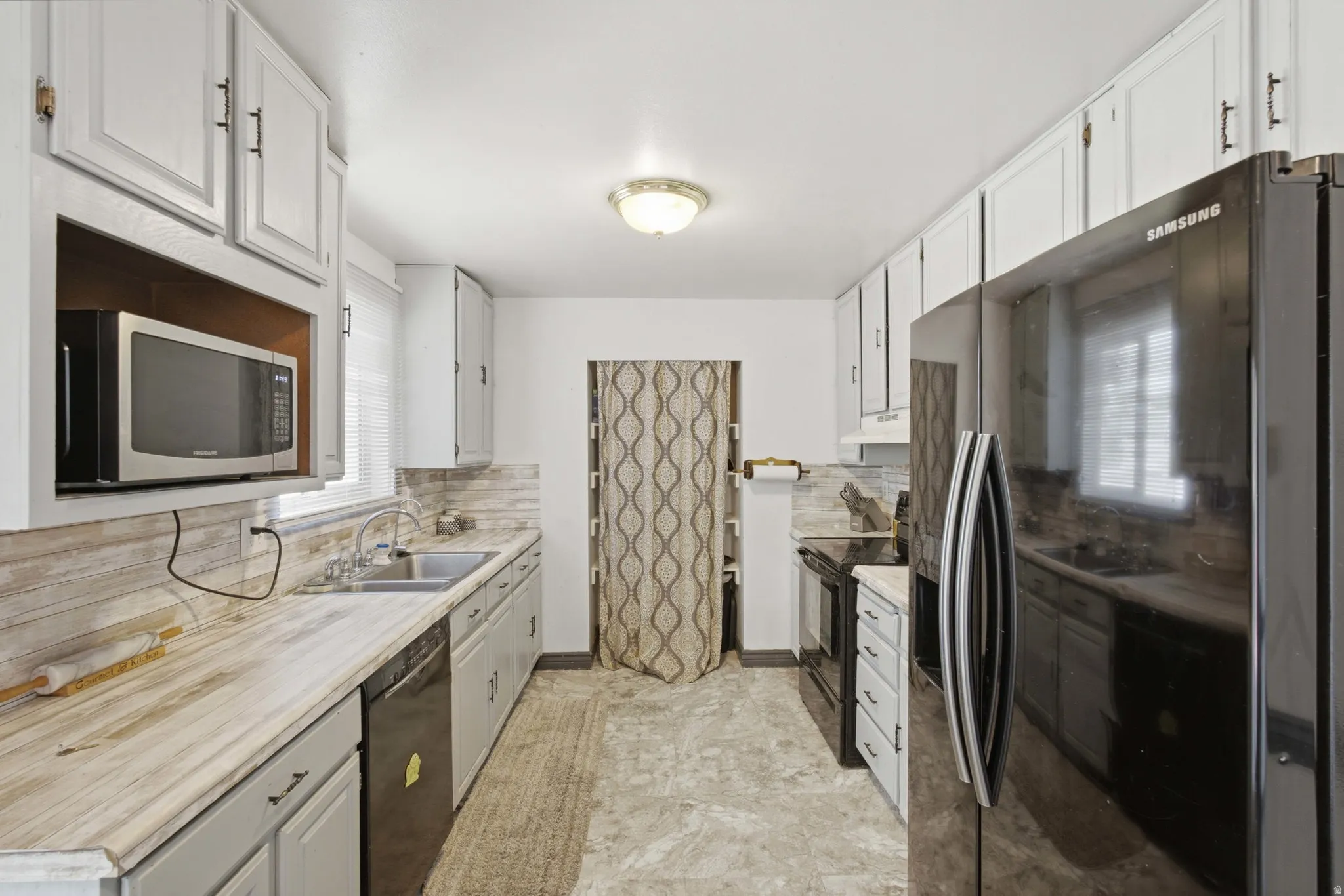 Galley kitchen featuring white upper cabinetry, gray lower cabinetry, and light-toned countertops