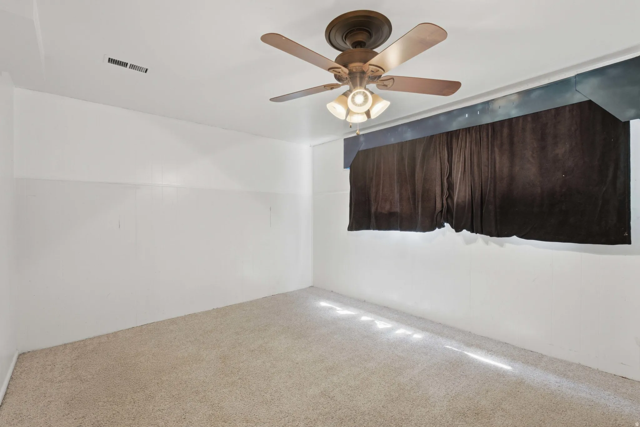 Room featuring wall-to-wall carpeting, white painted walls, and a ceiling fan with integrated lighting