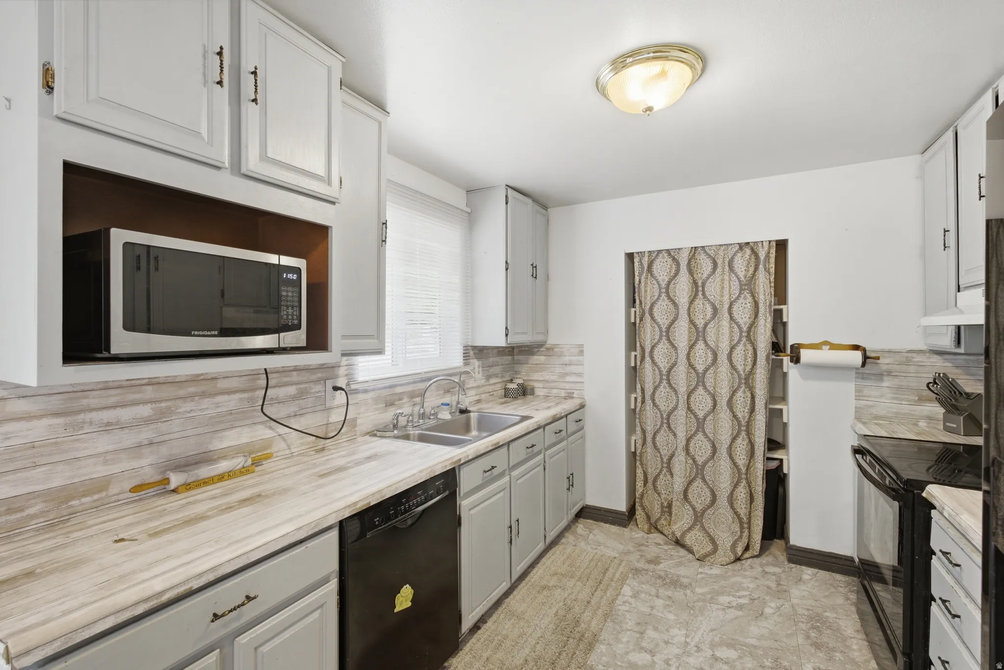 Kitchen featuring light gray cabinetry, wood-finish countertops, a stainless steel sink, a built-in microwave, and patterned flooring