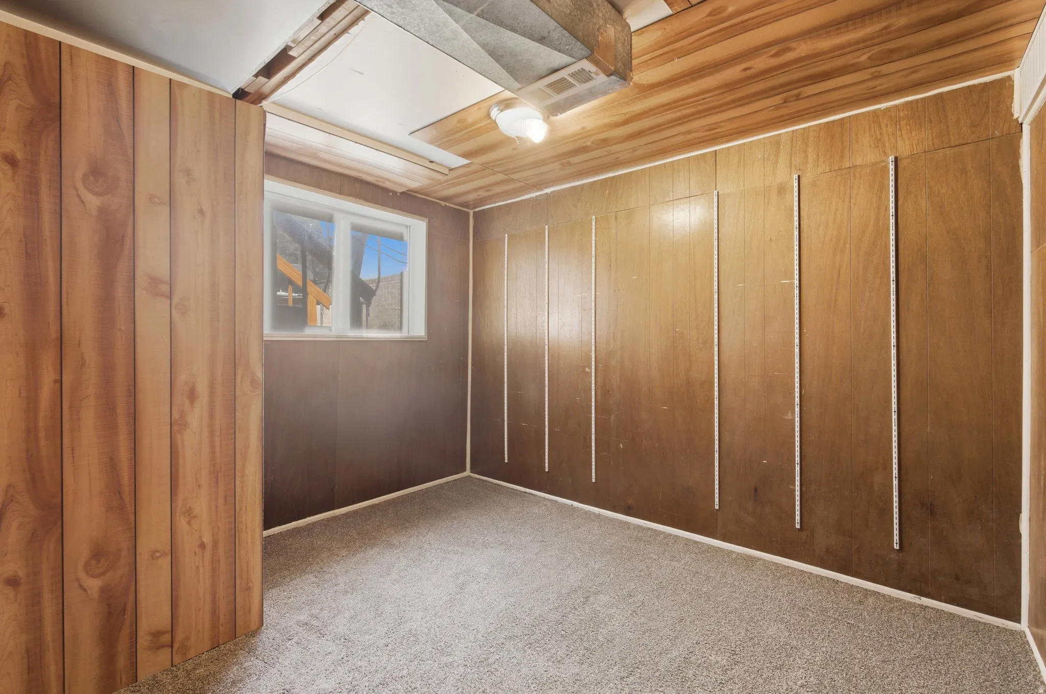 Room featuring light wood-finish paneled walls and a window