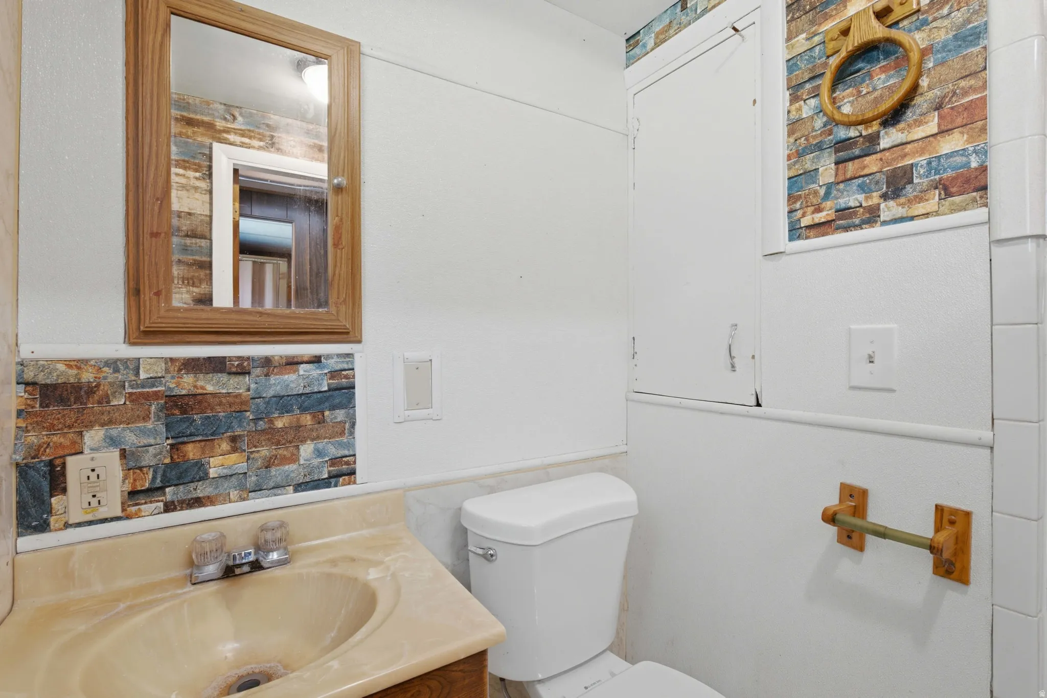 Bathroom vanity with integrated sink, framed medicine cabinet, and stone-look accent wall