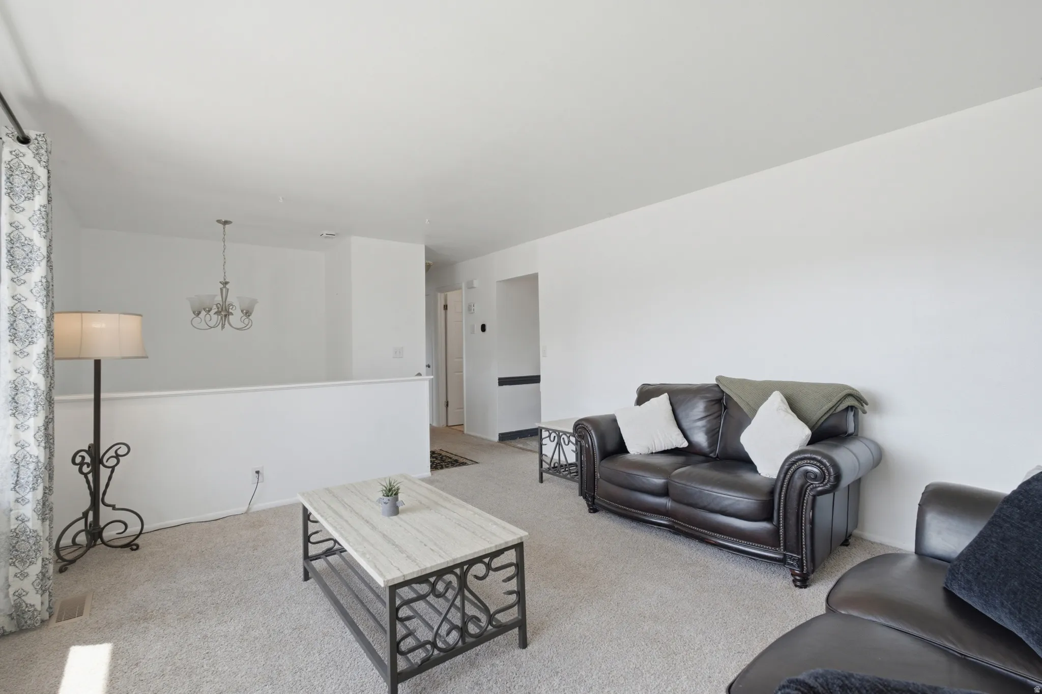 Carpeted living area featuring white painted walls and a partial wall partition