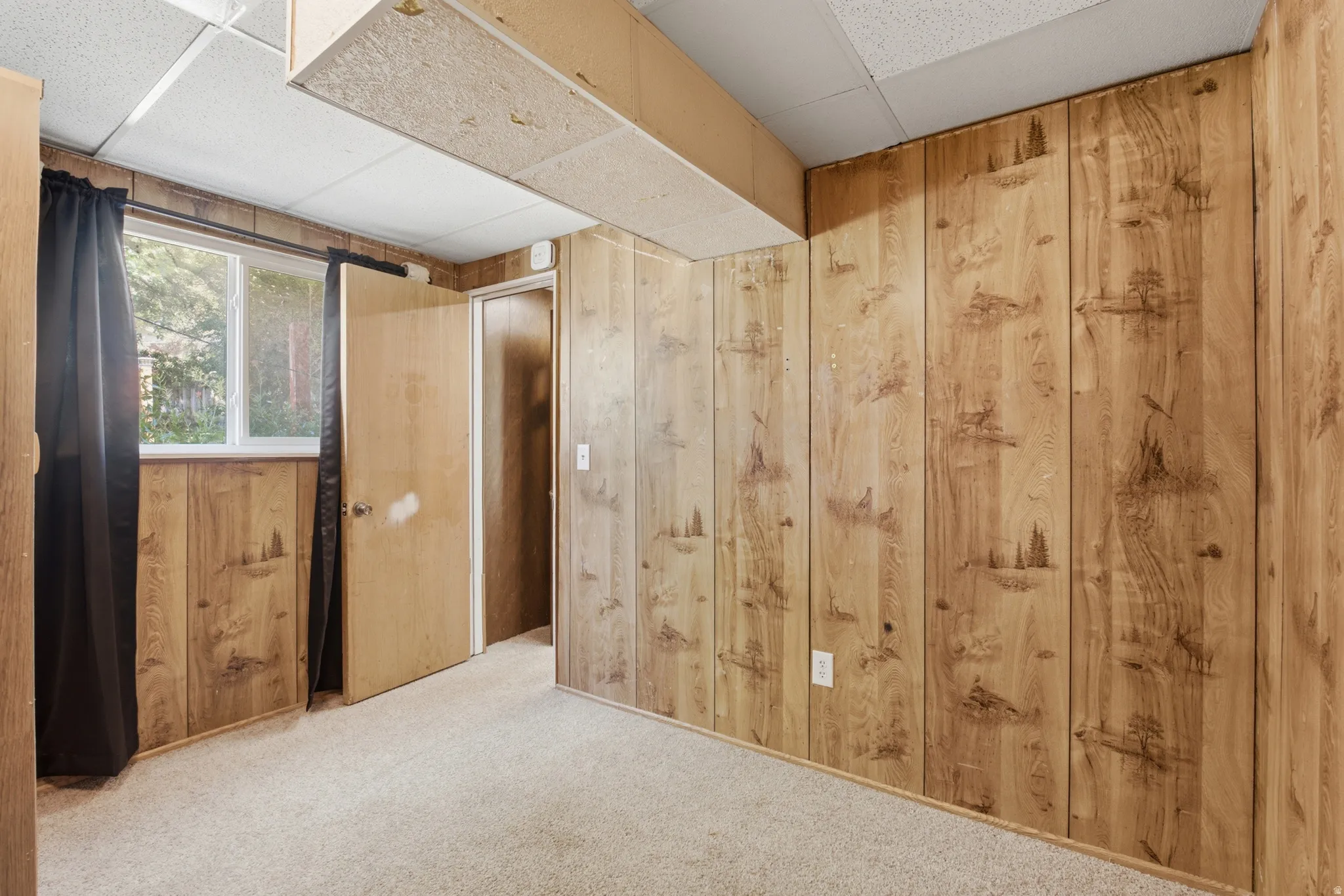 Carpeted room featuring wood-paneled walls with decorative etchings