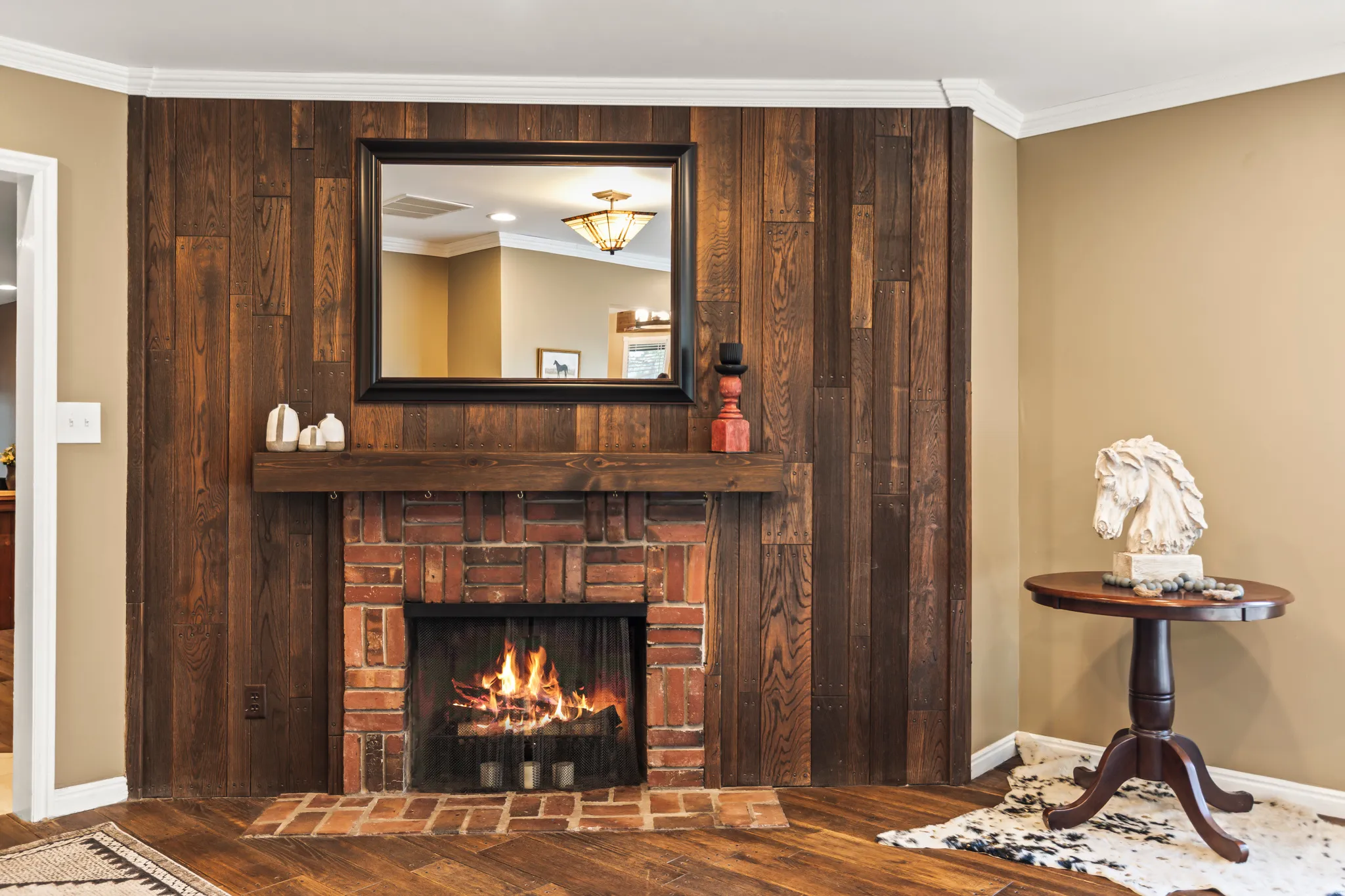 Brick fireplace with a substantial wood mantel, framed by a full wood-paneled accent wall
