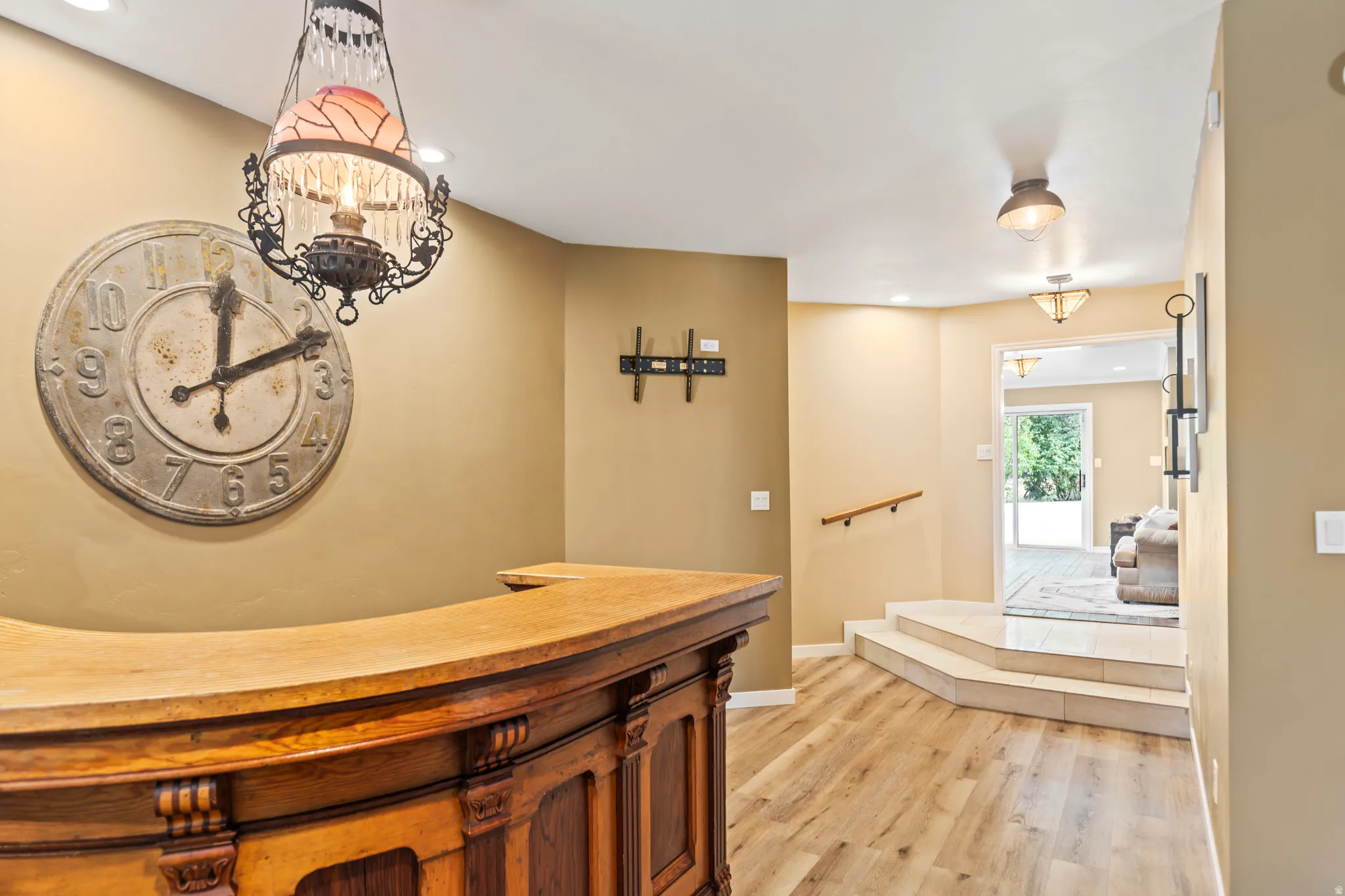 Curved wood-finish bar with ornate carving, wood-finish flooring, recessed lighting, and a decorative overhead fixture