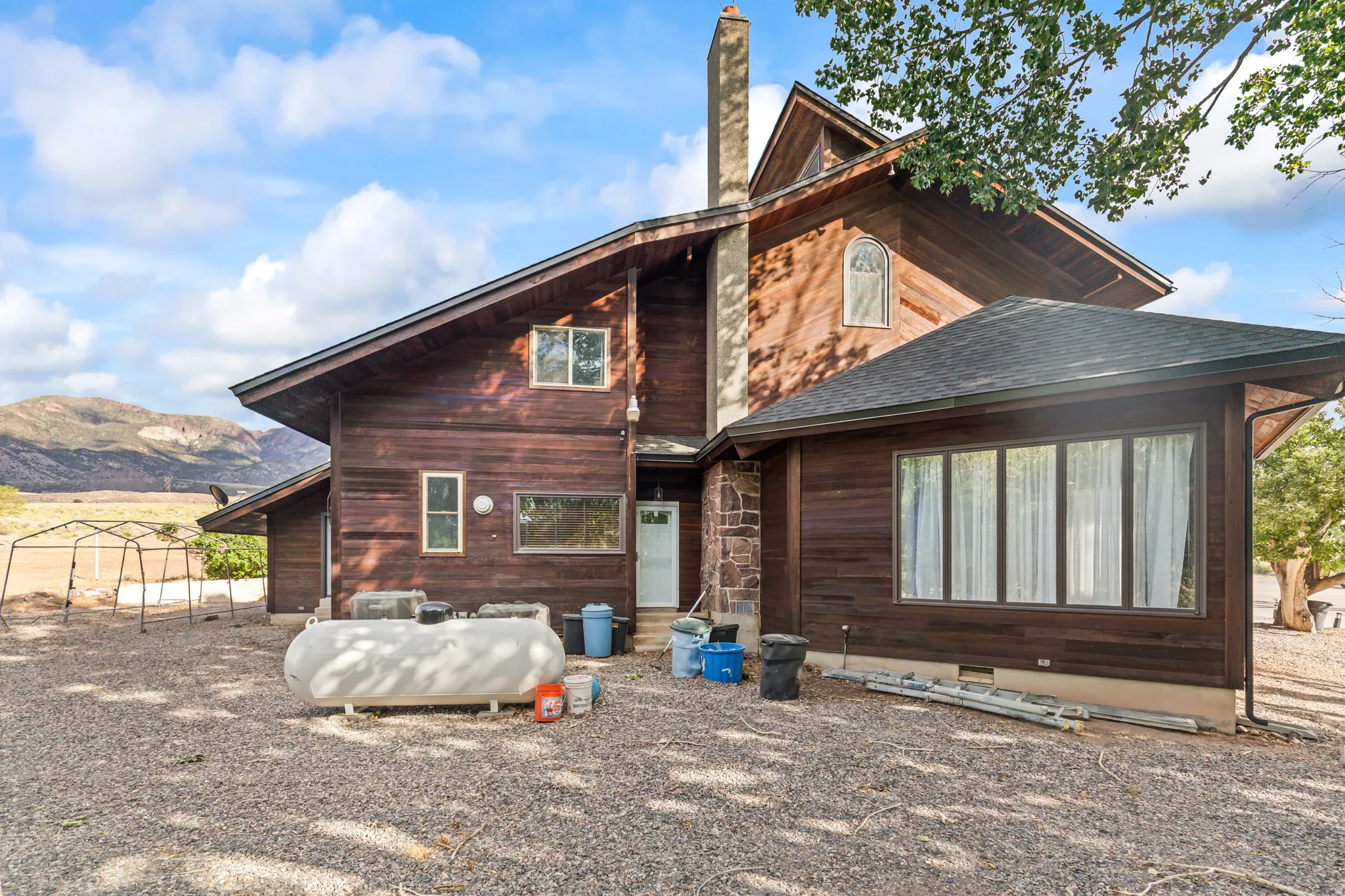 Wood-sided exterior featuring a prominent stone chimney and a multi-pitched roof