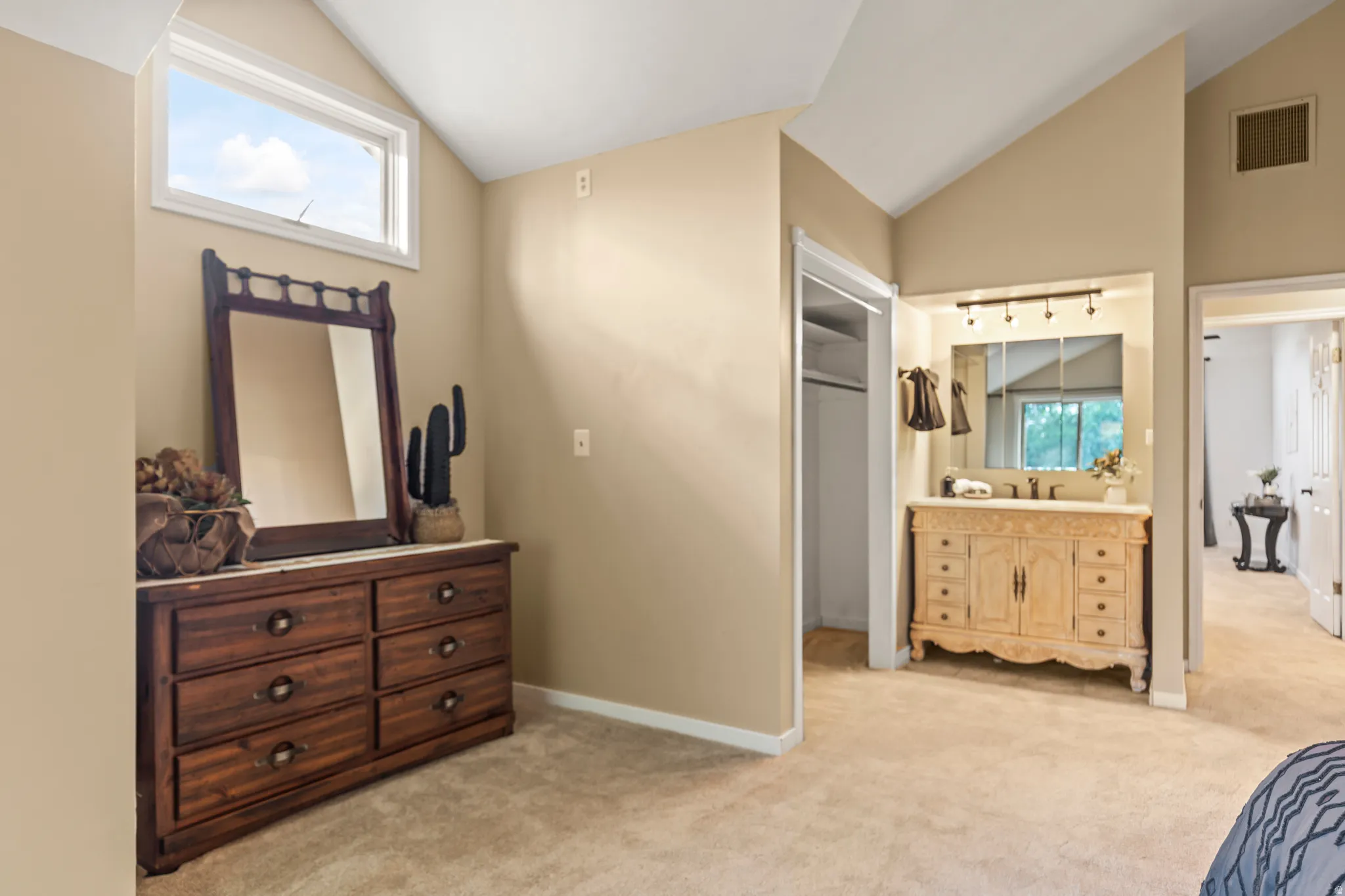 Vaulted ceiling room featuring a built-in vanity with a single sink, integrated mirror, and track lighting