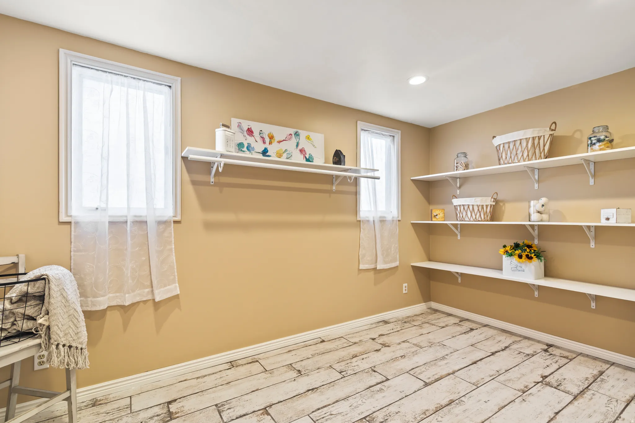 Room featuring extensive wall-mounted shelving, two windows, recessed ceiling lighting, and wood-finish flooring