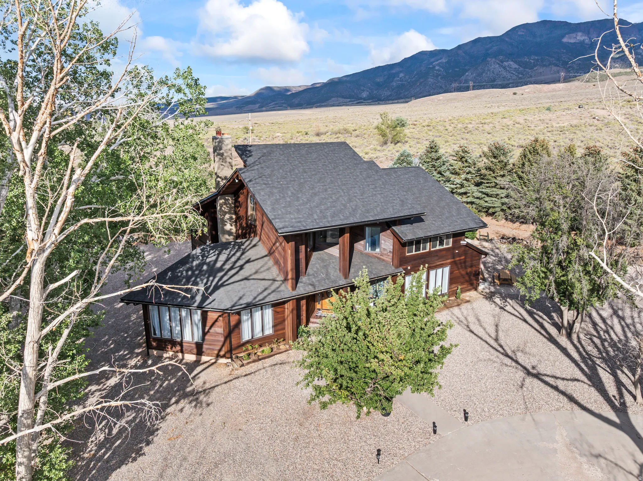 Stained wood-sided residence featuring a dark shingle roof and multiple windows