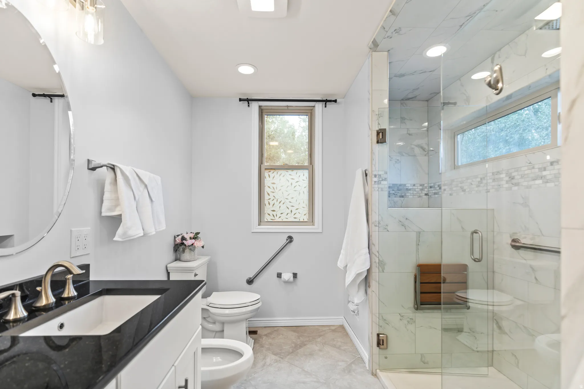 Bathroom featuring a dark stone countertop vanity with an undermount sink, a toilet, and a bidet