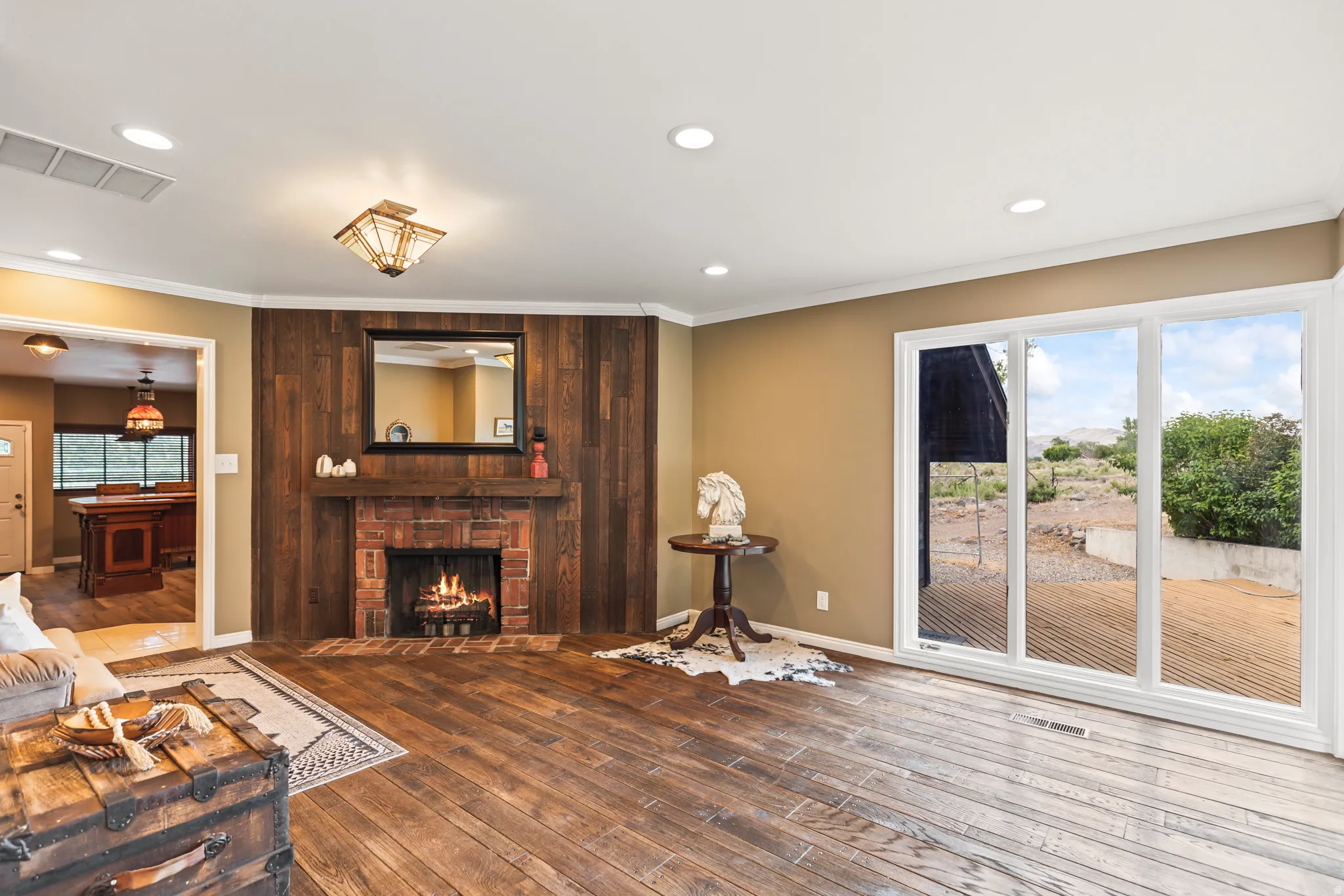 Living area featuring rich wood-finish flooring, a brick fireplace with wood paneling, and a large sliding glass door
