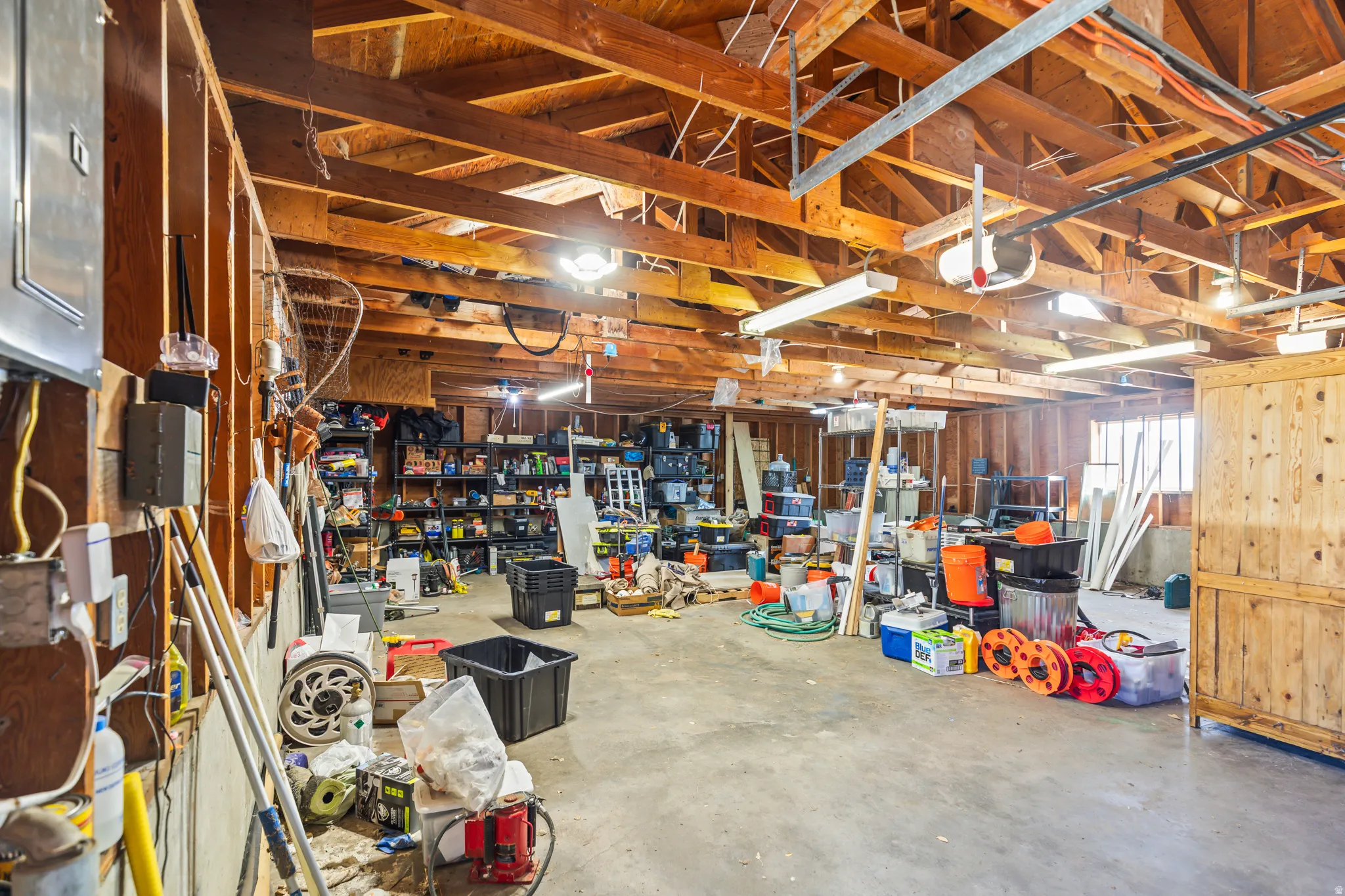 Spacious garage with exposed wood beam ceiling, concrete flooring, and ample storage potential