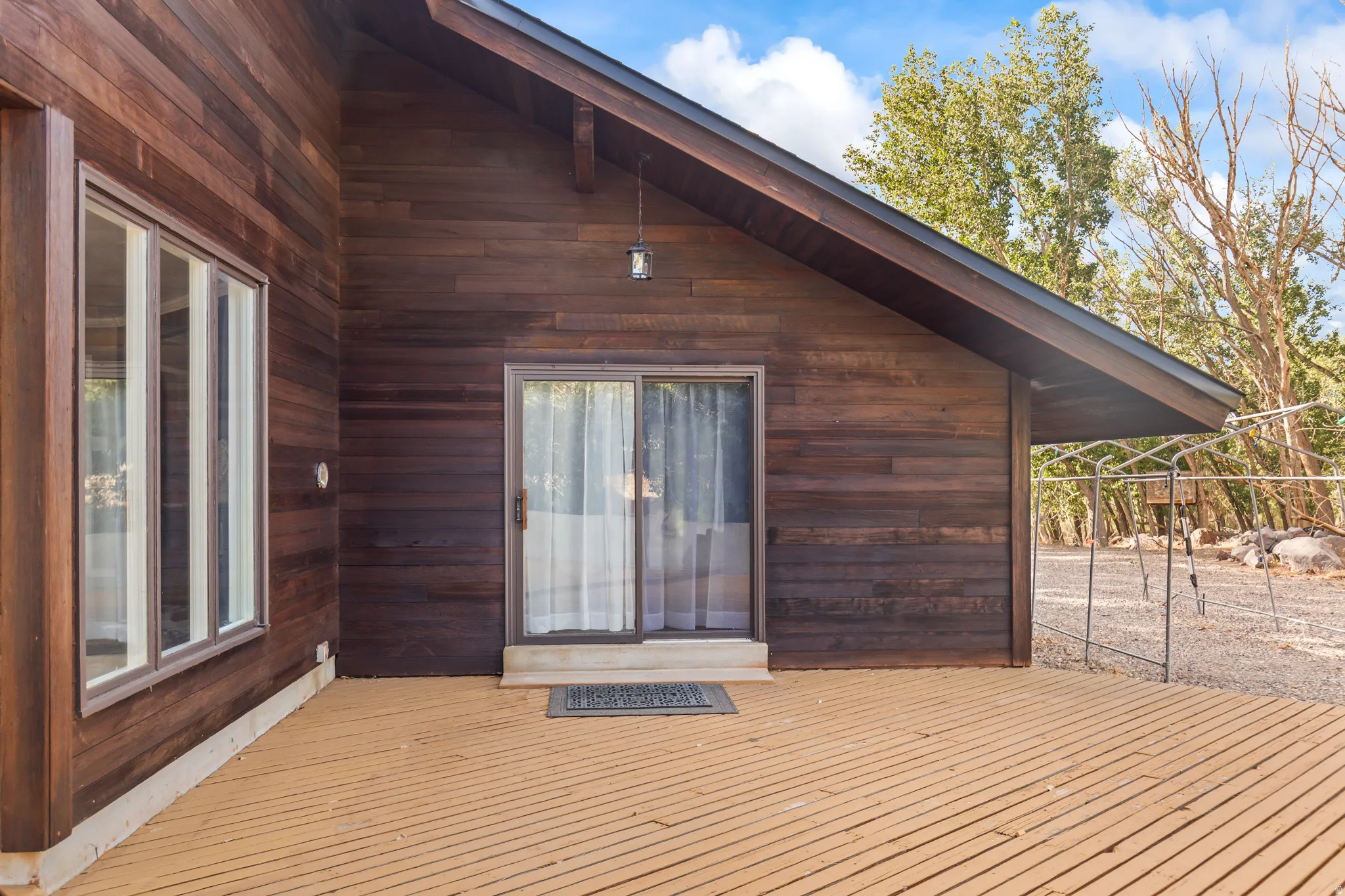 Wood-clad exterior featuring a pitched roofline, large window array, and sliding glass door