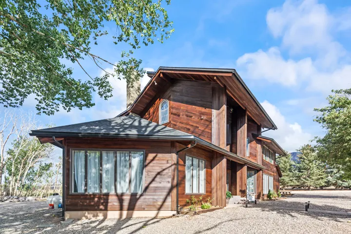 Wood-sided exterior featuring multiple windows, a prominent roofline, and a gravel driveway