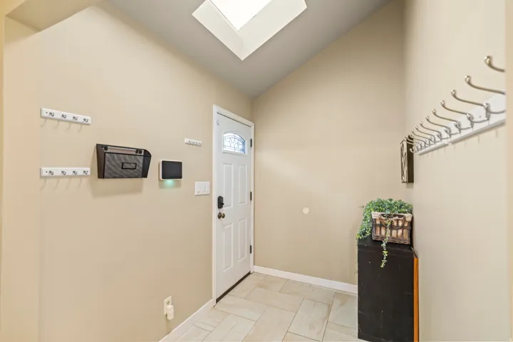 Entry foyer featuring a white paneled door with decorative glass inlay, overhead skylight, and angled ceiling