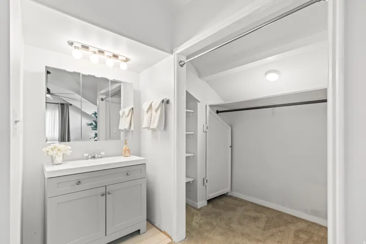 Bathroom vanity with a white countertop and gray shaker-style cabinetry, featuring a medicine cabinet and a four-bulb vanity light
