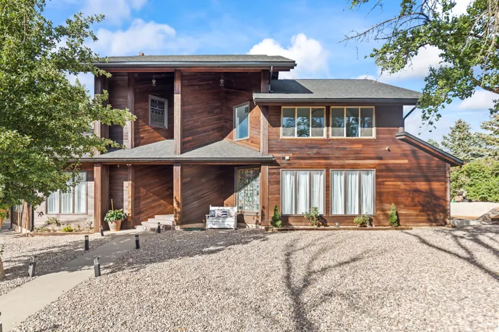 Multi-level wood-clad exterior with a prominent covered entryway, multiple windows, and a paved walkway