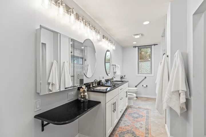 Double vanity with dark countertops, dual rectangular sinks, brushed nickel faucets, and under-sink storage