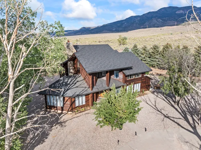 Stained wood-sided residence featuring a dark shingle roof and multiple windows
