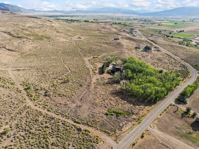 Extensive land parcel featuring established trees and a paved road frontage