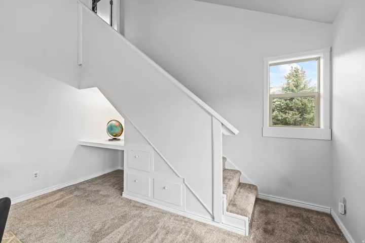 Carpeted staircase featuring white risers and a matching handrail