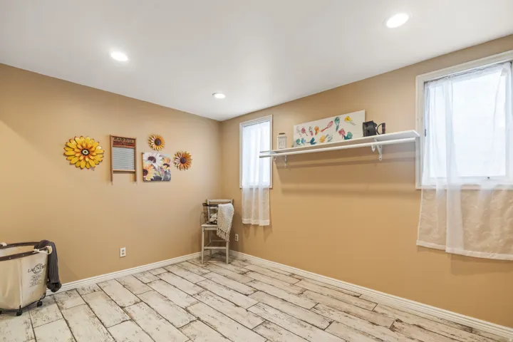 Room with distressed wood-finish flooring, recessed lighting, and two windows