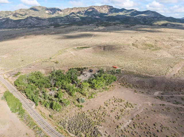 Expansive rural property featuring a paved road frontage, mature trees, open land, and mountain backdrop
