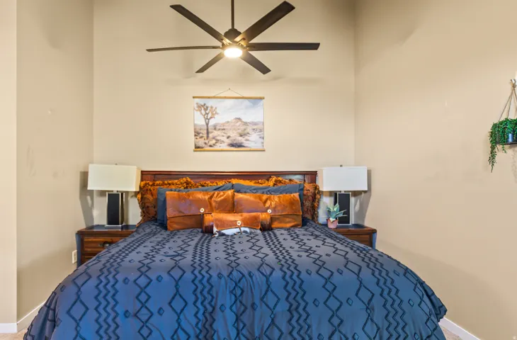 Bedroom featuring a dark wood headboard, a ceiling fan with integrated lighting, and neutral wall tones