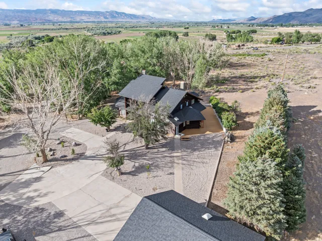 Expansive property featuring a dark-toned residence with multiple gables and a gravel driveway