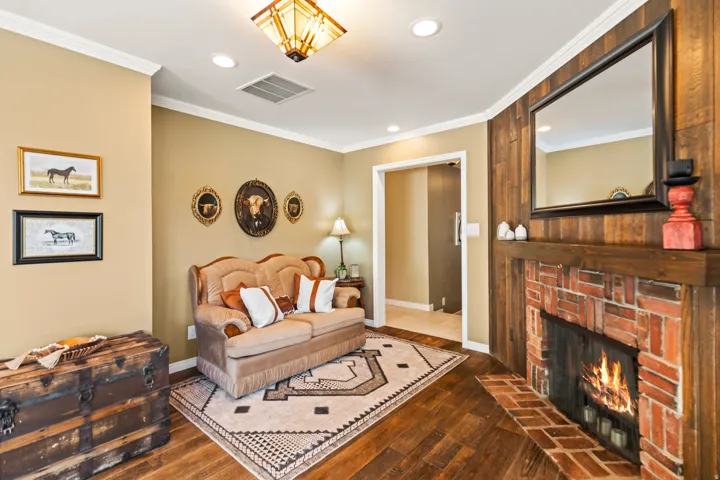 Living area featuring a brick fireplace with a wood mantle, wood-finish flooring, and recessed lighting