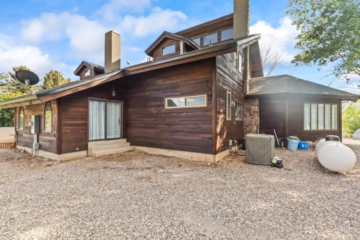 Exterior featuring wood siding, a gravel-covered ground surface, and multiple windows