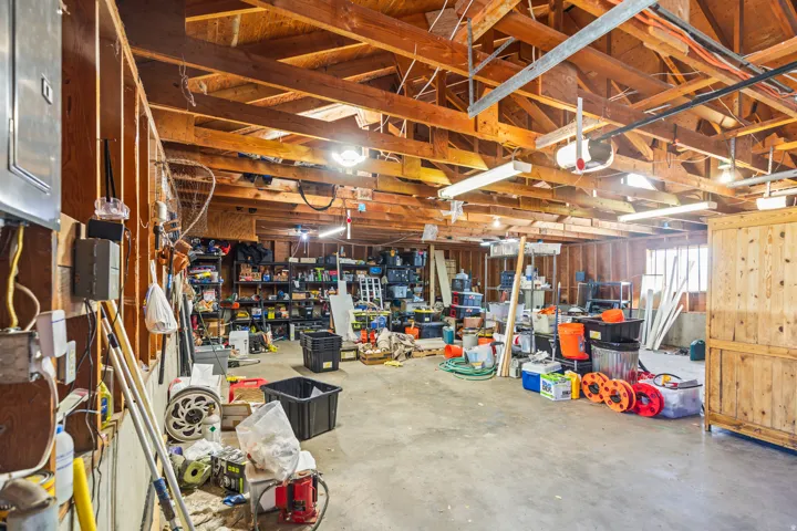 Spacious garage with exposed wood beam ceiling, concrete flooring, and ample storage potential