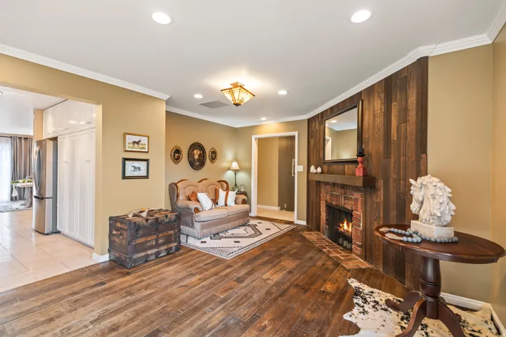 Living area featuring a brick fireplace with wood mantel, recessed lighting, and wood-finish flooring