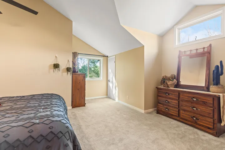 Carpeted room featuring a sloped ceiling and multiple windows providing ample natural light