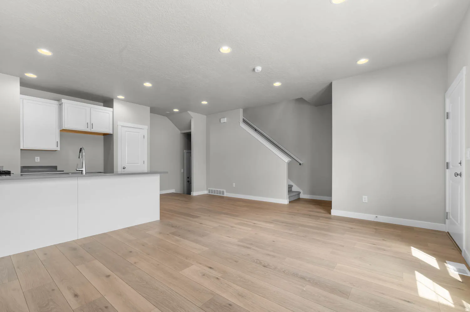 Open-concept living space featuring wood-finish flooring, recessed lighting, and white trim