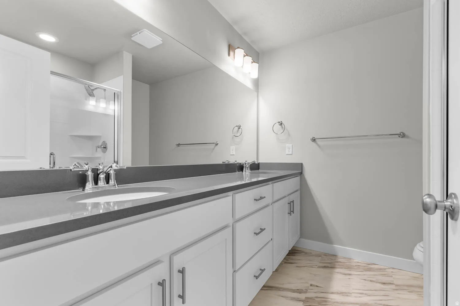 Bathroom featuring a dual vanity with white cabinetry, integrated sinks, and a large mirror