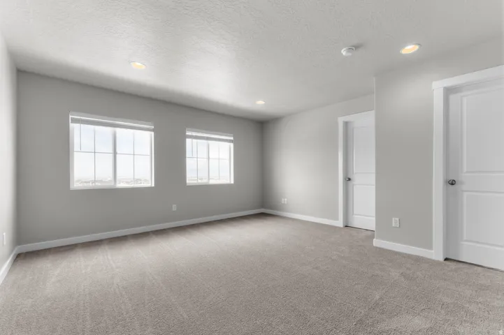 Spacious room featuring neutral carpeting, light gray wall paint, and white trim