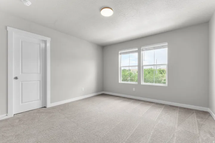 Spacious room featuring neutral carpeting, light gray walls, white trim, and two large windows with blinds