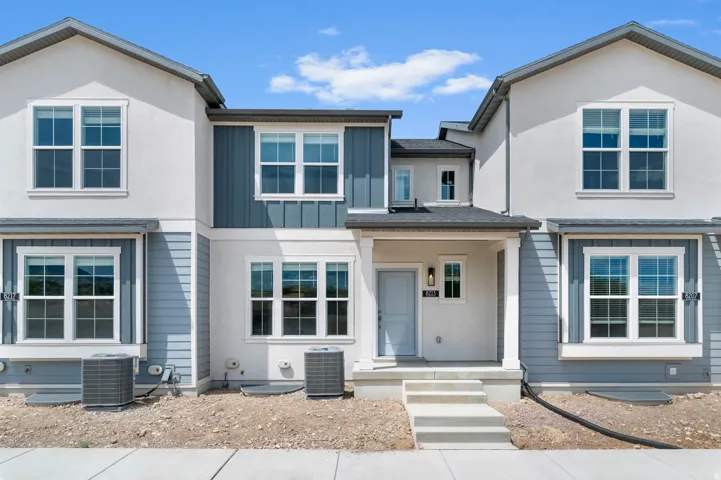 Contemporary townhome exterior featuring light-colored stucco and light blue horizontal siding