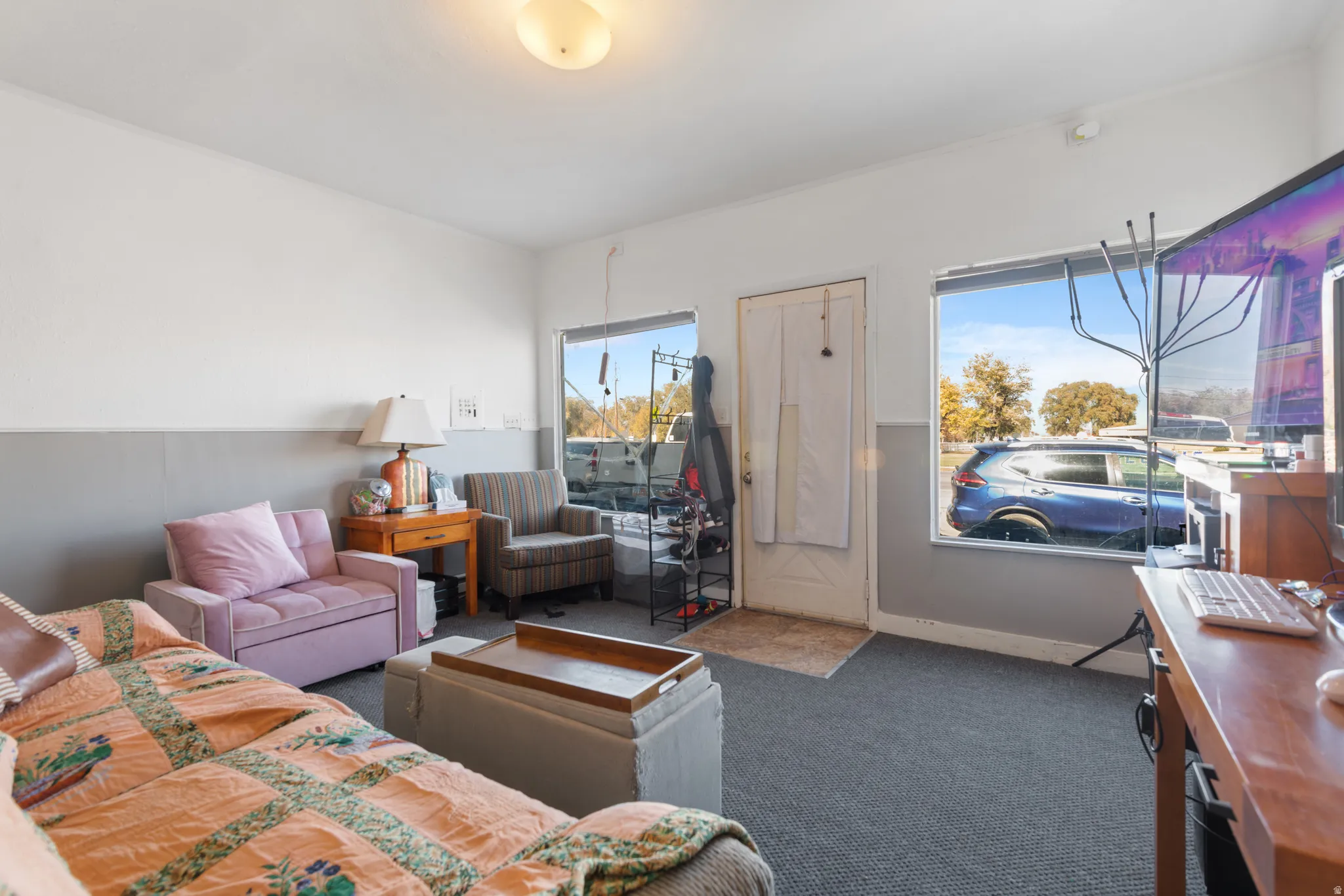 Carpeted interior space with a two-tone wall treatment, featuring a large window and a white entry door
