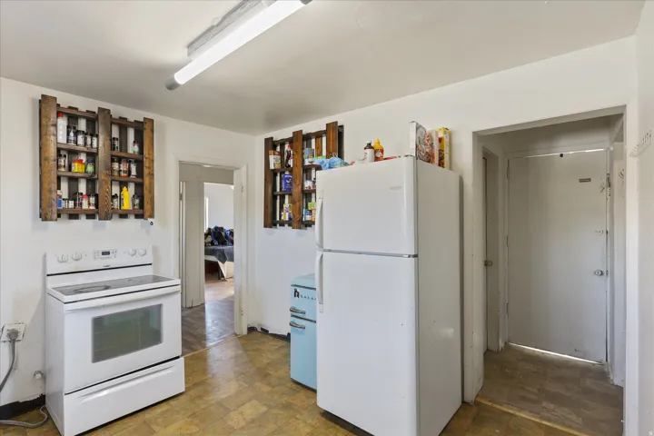 Kitchen featuring a white electric range, white top-freezer refrigerator, and two wall-mounted wooden shelving units