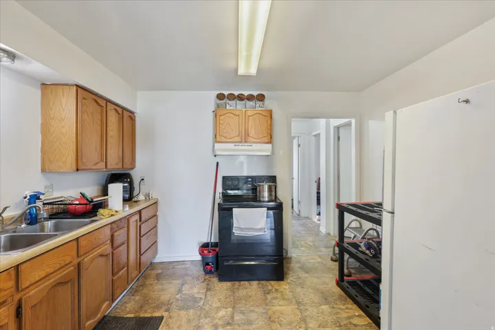 Kitchen featuring wood cabinetry, a stainless steel sink, and a black electric range
