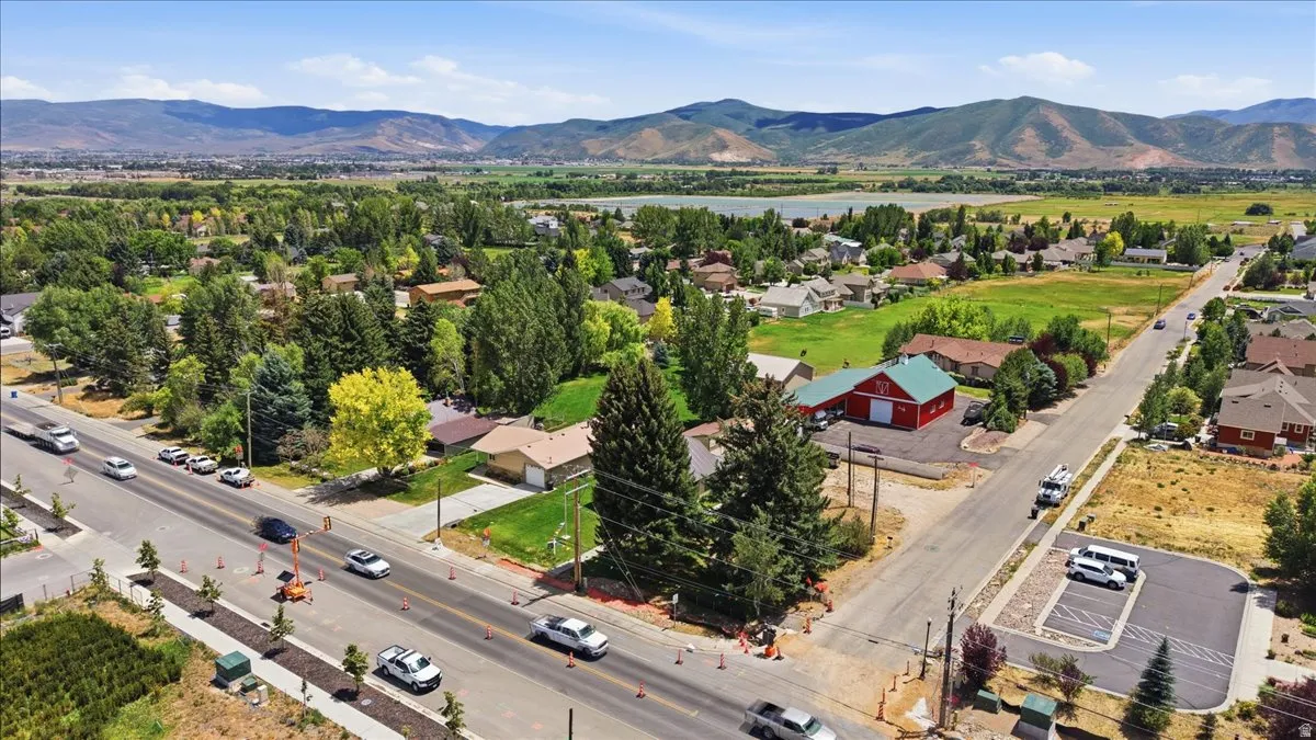 Expansive aerial capturing a vibrant community setting with residential homes, mature trees, and a prominent red barn structure