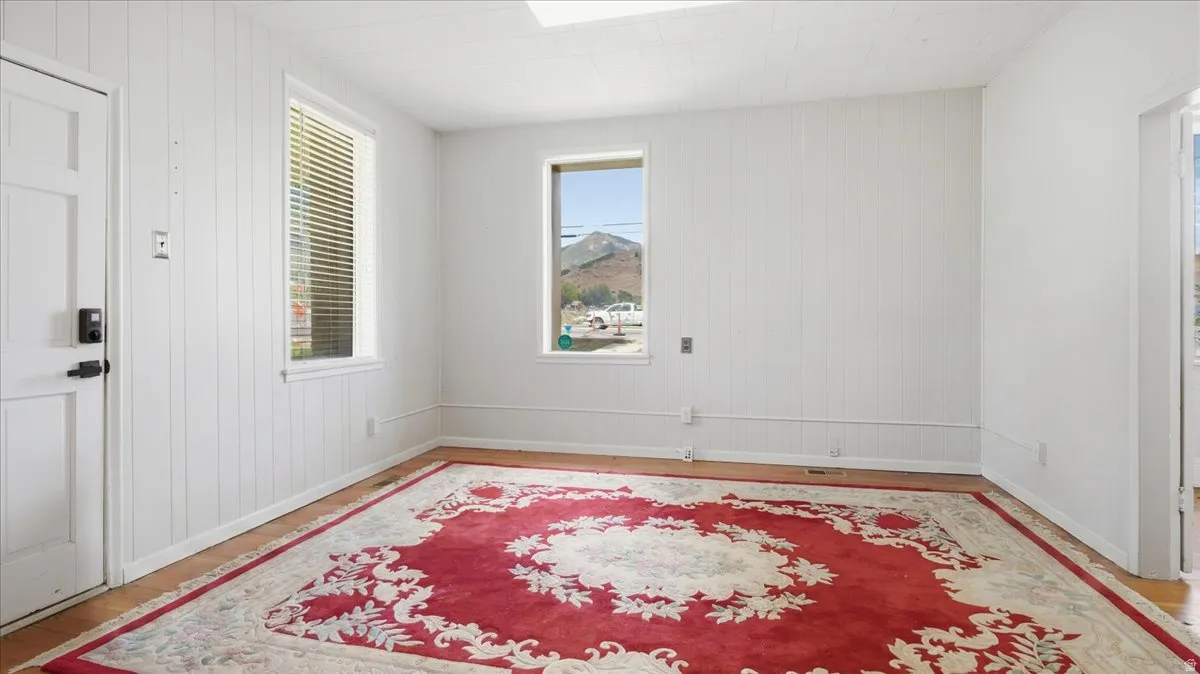 Bright room featuring two windows, vertical paneling, and wood-finish flooring